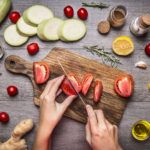 Female hand cut tomatoes rustic kitchen table,vegetarian concept.